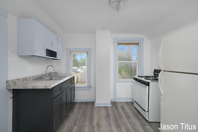 kitchen with light hardwood / wood-style floors, white appliances, and sink