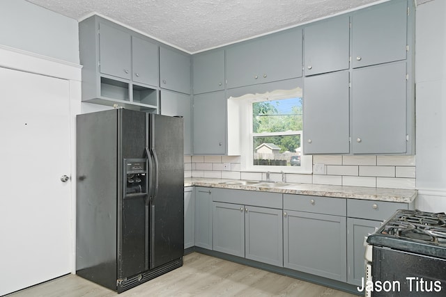 kitchen with tasteful backsplash, gray cabinetry, sink, black appliances, and light hardwood / wood-style floors