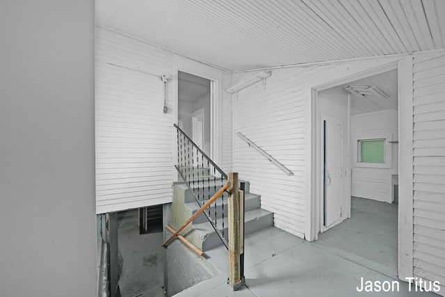 staircase with lofted ceiling and concrete floors