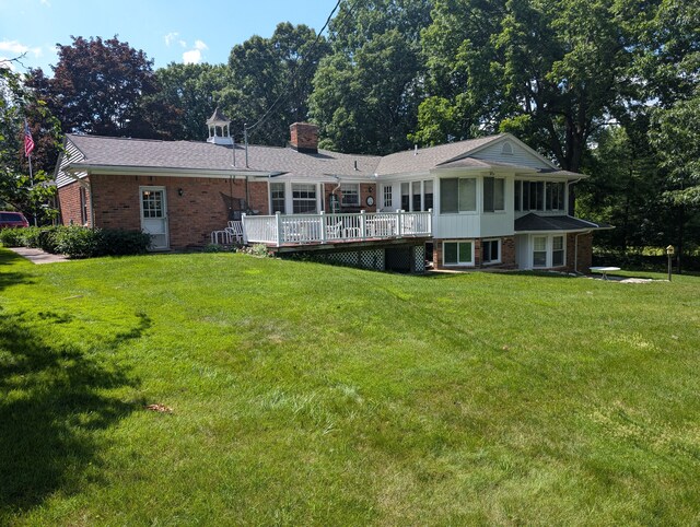 3641 Green Lake Rd, West Bloomfield, MI 48324 - rear view of property with brick siding, a wooden deck, a lawn, and a sunroom
