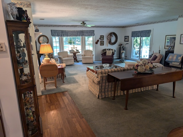 living room with ceiling fan, plenty of natural light, wood-type flooring, and a textured ceiling