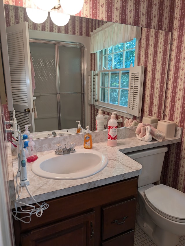 bathroom featuring tile patterned floors, a shower with door, vanity, and toilet