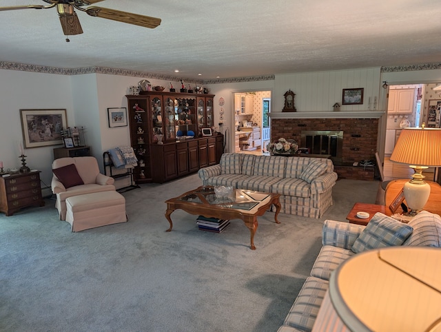 living room with ceiling fan, a fireplace, carpet, and a textured ceiling