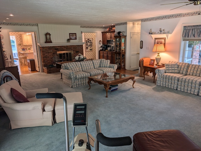 living room featuring a fireplace, light carpet, a textured ceiling, and ceiling fan