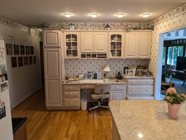 kitchen featuring light stone countertops, built in desk, and light wood-type flooring