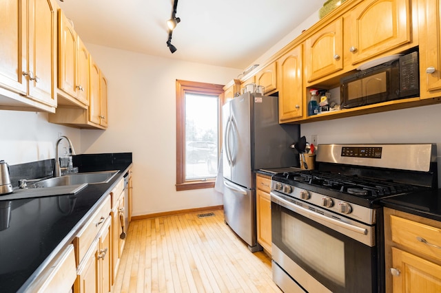 kitchen featuring sink, rail lighting, light wood-type flooring, and appliances with stainless steel finishes