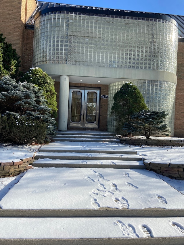 snow covered property entrance featuring french doors