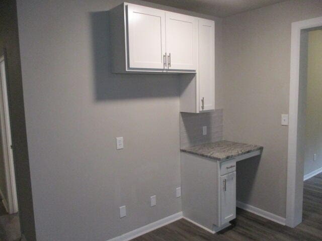 kitchen featuring white cabinets, dark hardwood / wood-style floors, and light stone counters