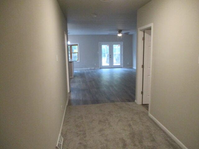 corridor with dark colored carpet and french doors