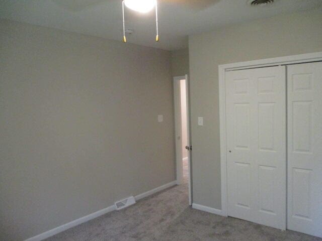 unfurnished bedroom with light carpet, a closet, and ceiling fan