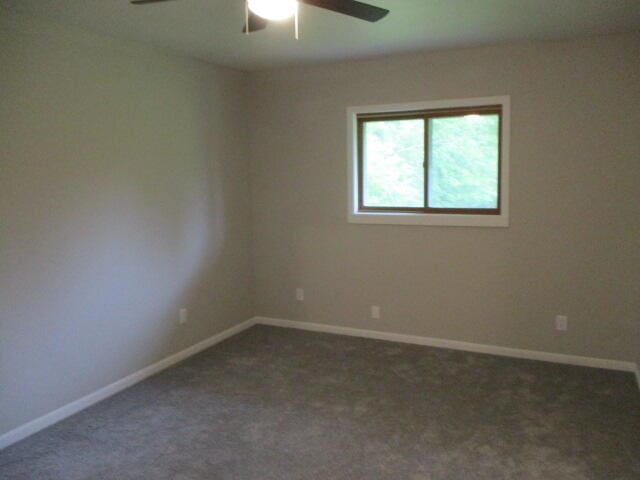 spare room featuring ceiling fan and dark colored carpet