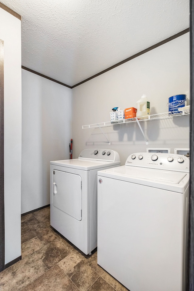 washroom featuring a textured ceiling, washer and clothes dryer, and crown molding