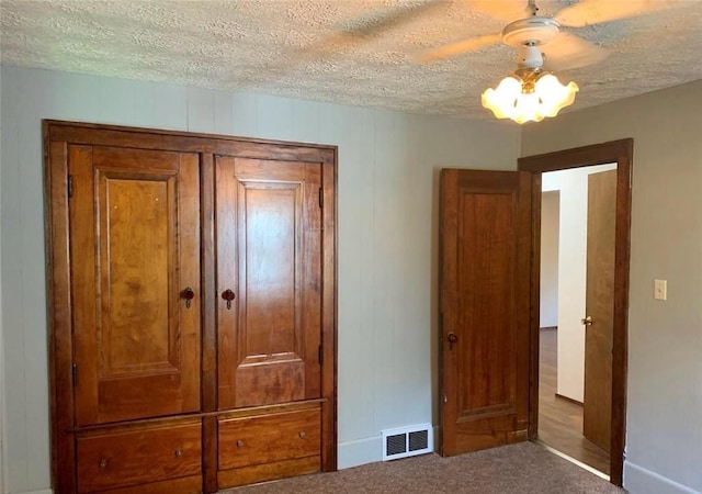 unfurnished bedroom featuring ceiling fan, a textured ceiling, and dark colored carpet