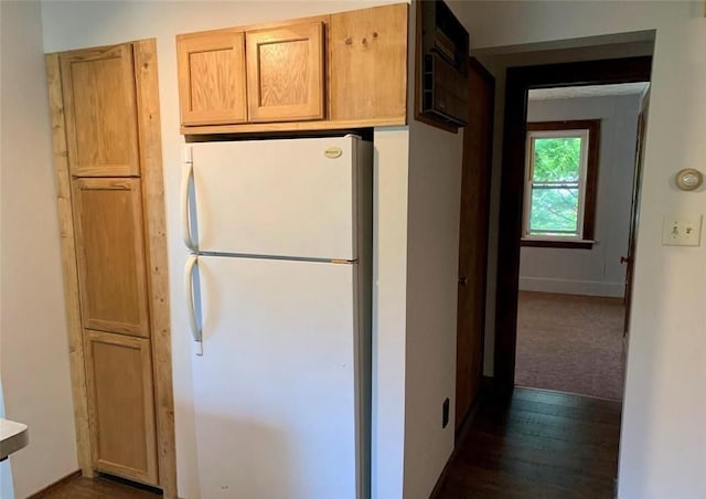 kitchen with light brown cabinetry, white fridge, and dark wood-type flooring