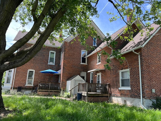 back of house with a storage unit and a deck