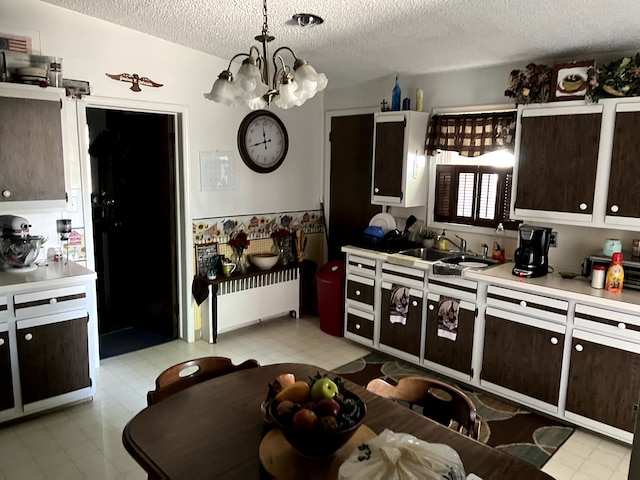 kitchen with an inviting chandelier, sink, hanging light fixtures, a textured ceiling, and dark brown cabinets