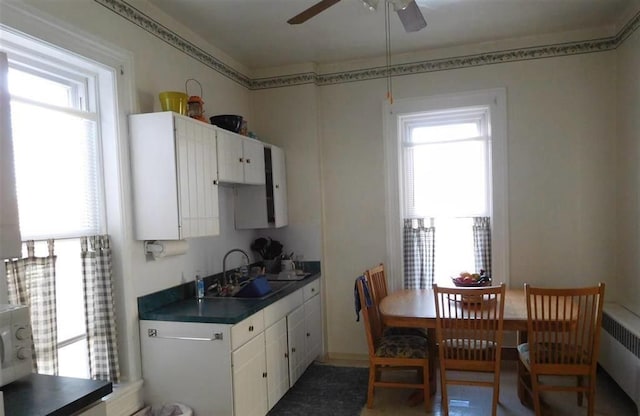 kitchen featuring a healthy amount of sunlight, white cabinetry, sink, and radiator