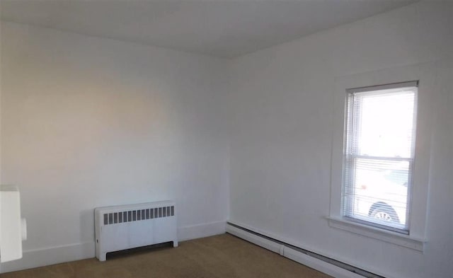 carpeted empty room featuring radiator and a baseboard heating unit