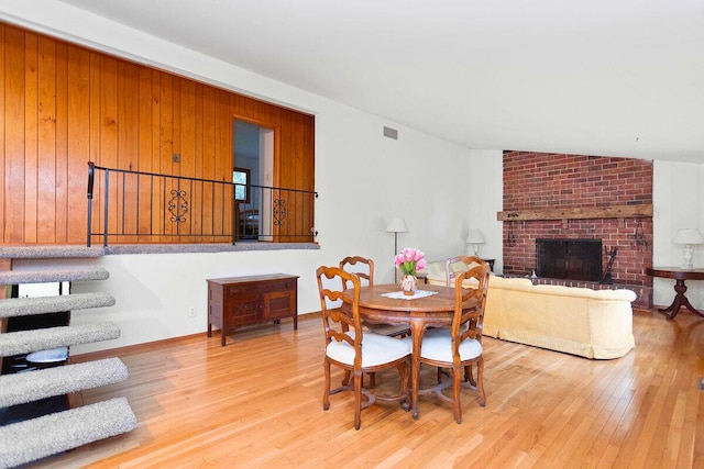 dining area featuring a fireplace, light hardwood / wood-style floors, and lofted ceiling