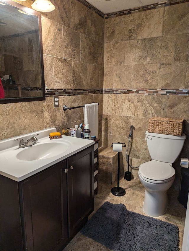 bathroom featuring vanity, tile walls, and toilet