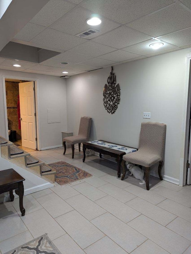 living area featuring light tile patterned floors and a paneled ceiling