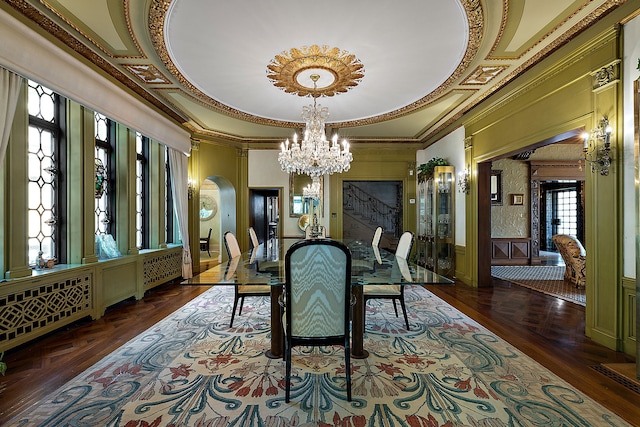 dining space with a raised ceiling, crown molding, dark hardwood / wood-style flooring, and an inviting chandelier