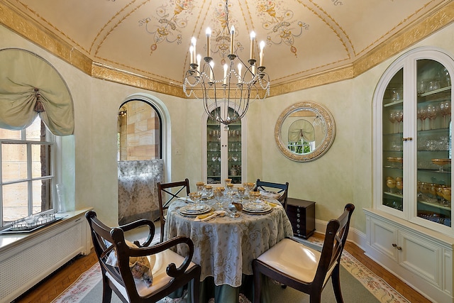 dining area featuring a notable chandelier, lofted ceiling, and hardwood / wood-style flooring