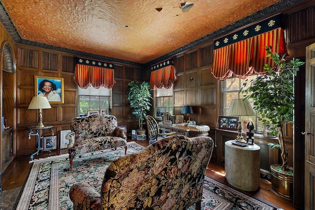 living area featuring wood walls, crown molding, a textured ceiling, and hardwood / wood-style flooring