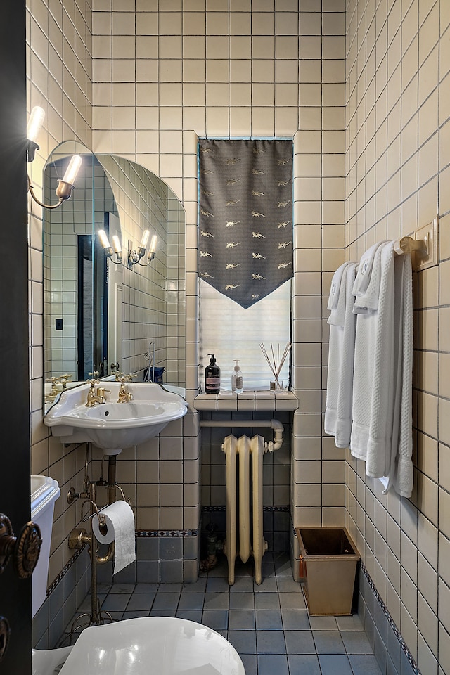 bathroom featuring tile patterned floors, radiator heating unit, and tile walls