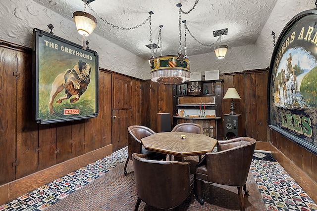 dining room with a textured ceiling and wooden walls