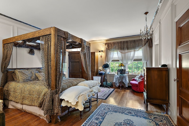 bedroom with hardwood / wood-style floors, ornamental molding, and a notable chandelier