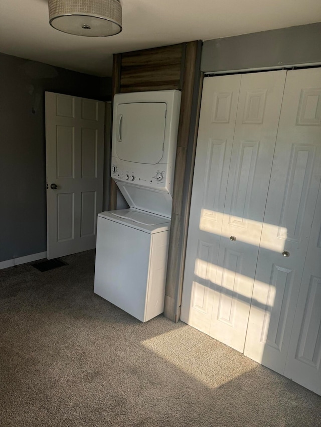 clothes washing area with carpet and stacked washing maching and dryer