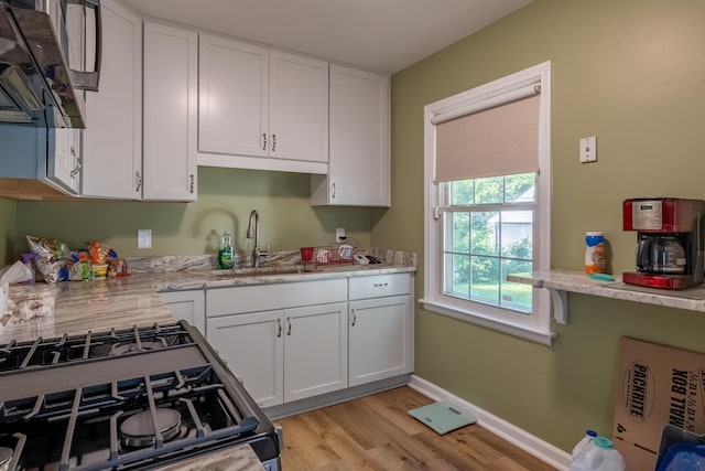 kitchen featuring white cabinets, light stone counters, sink, and light hardwood / wood-style flooring