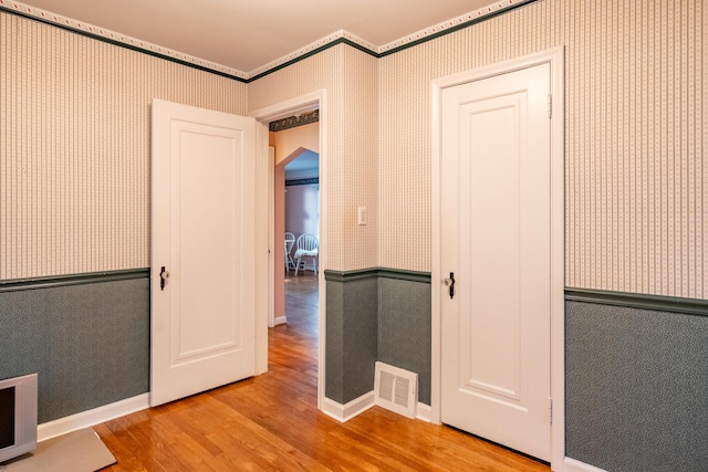 hallway with light hardwood / wood-style flooring and ornamental molding