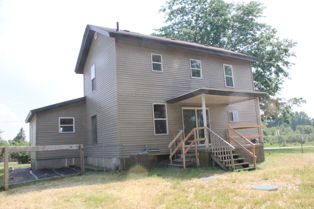 rear view of house with central AC and a yard