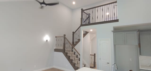 staircase featuring ceiling fan, sink, and a high ceiling