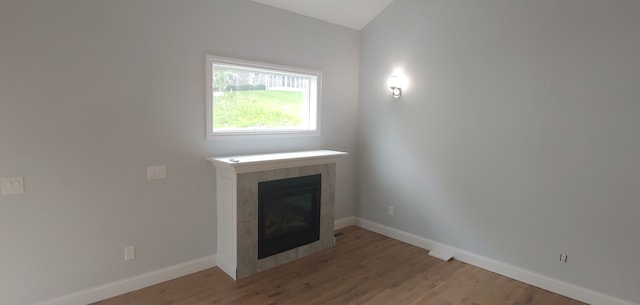 unfurnished living room with a tiled fireplace and hardwood / wood-style floors