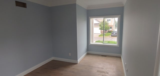 spare room with light wood-type flooring and crown molding