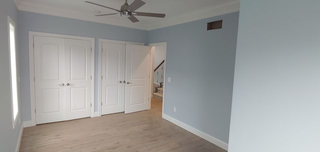 unfurnished bedroom with light hardwood / wood-style floors, ceiling fan, and multiple closets