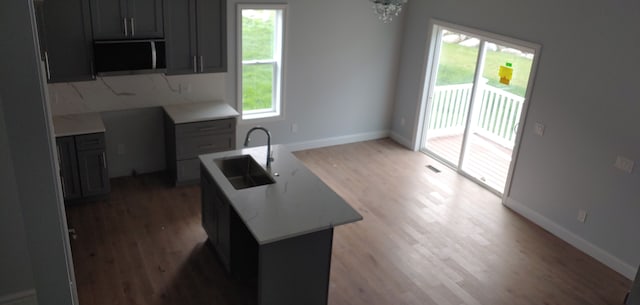 kitchen with sink, a chandelier, dark hardwood / wood-style floors, and a center island with sink