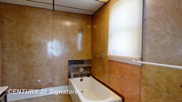 bathroom with a bathtub, vanity, and a drop ceiling