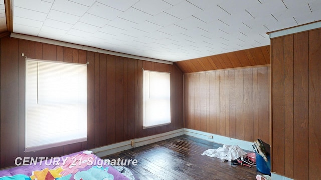 unfurnished bedroom with lofted ceiling, wood walls, and dark hardwood / wood-style floors