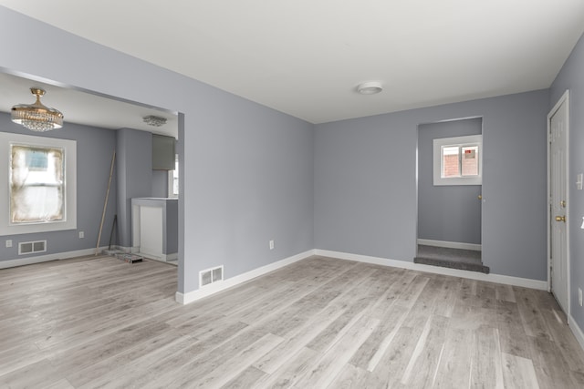 13437 E State Fair St, Detroit, MI 48205 - unfurnished living room featuring light wood finished floors, baseboards, and a chandelier