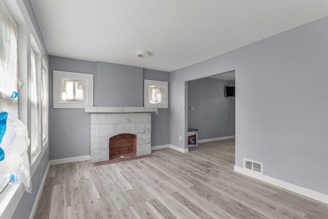 13437 E State Fair St, Detroit, MI 48205 - unfurnished living room with a tiled fireplace, light wood-type flooring, and baseboards