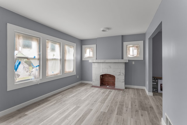 unfurnished living room with a tiled fireplace and light hardwood / wood-style floors