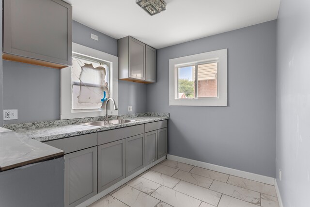 13437 E State Fair St, Detroit, MI 48205 - kitchen with a sink, light marble finish flooring, gray cabinets, and baseboards