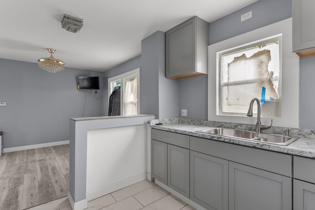 kitchen featuring gray cabinets, sink, and light wood-type flooring