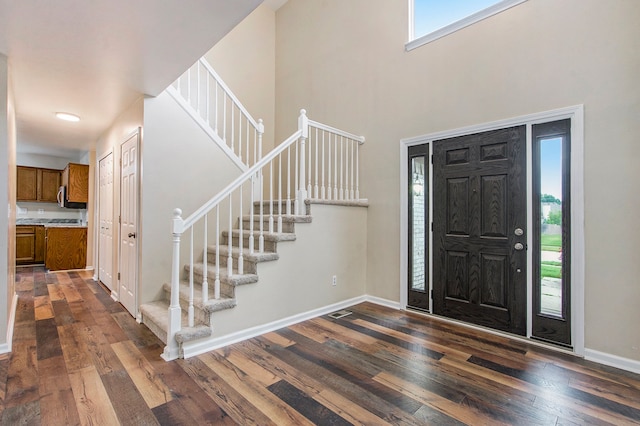 foyer entrance with dark hardwood / wood-style flooring and a towering ceiling