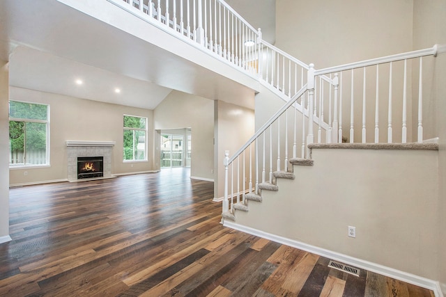 stairway featuring a tiled fireplace, hardwood / wood-style floors, and high vaulted ceiling