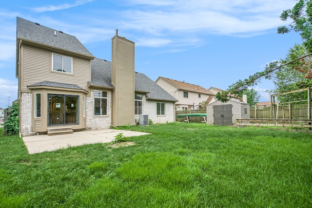 back of house featuring a shed, central AC, a patio area, and a lawn